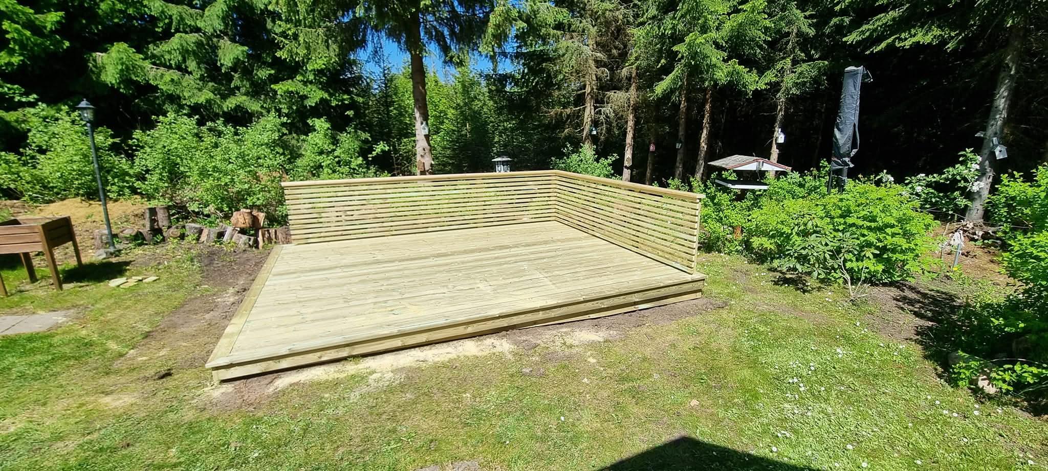 Nieuw terras in geïmpregneerd hout met schutting tegen het sparrenbos