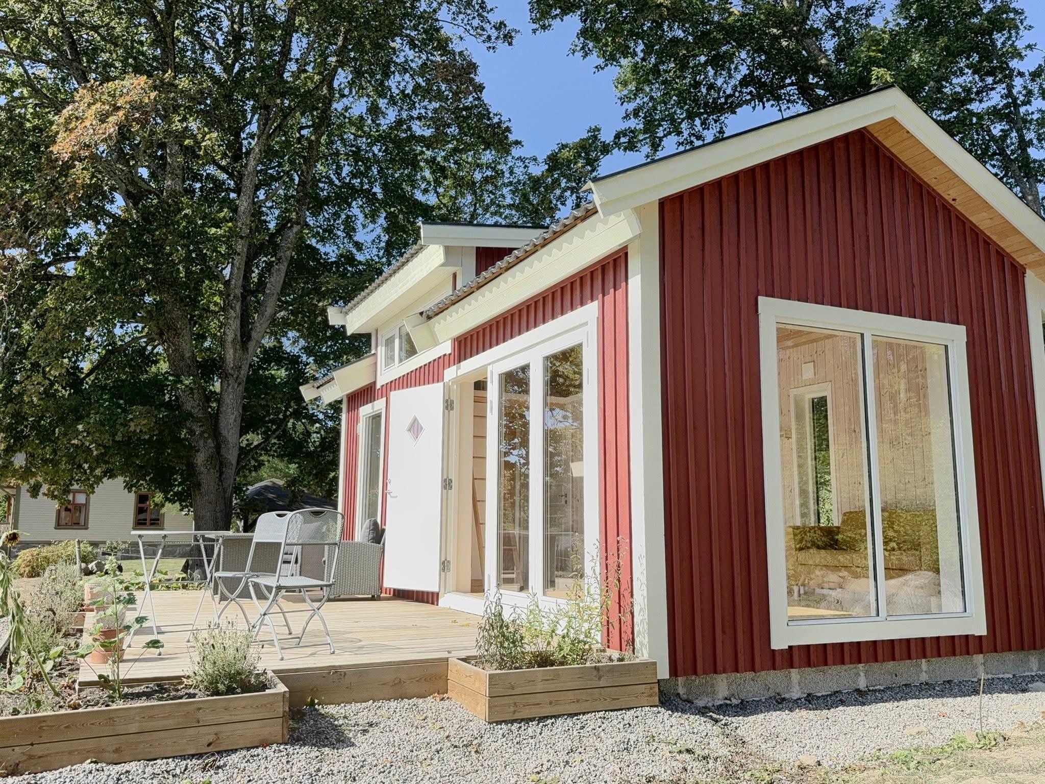 Red attefallshus with large glazing and a timber deck