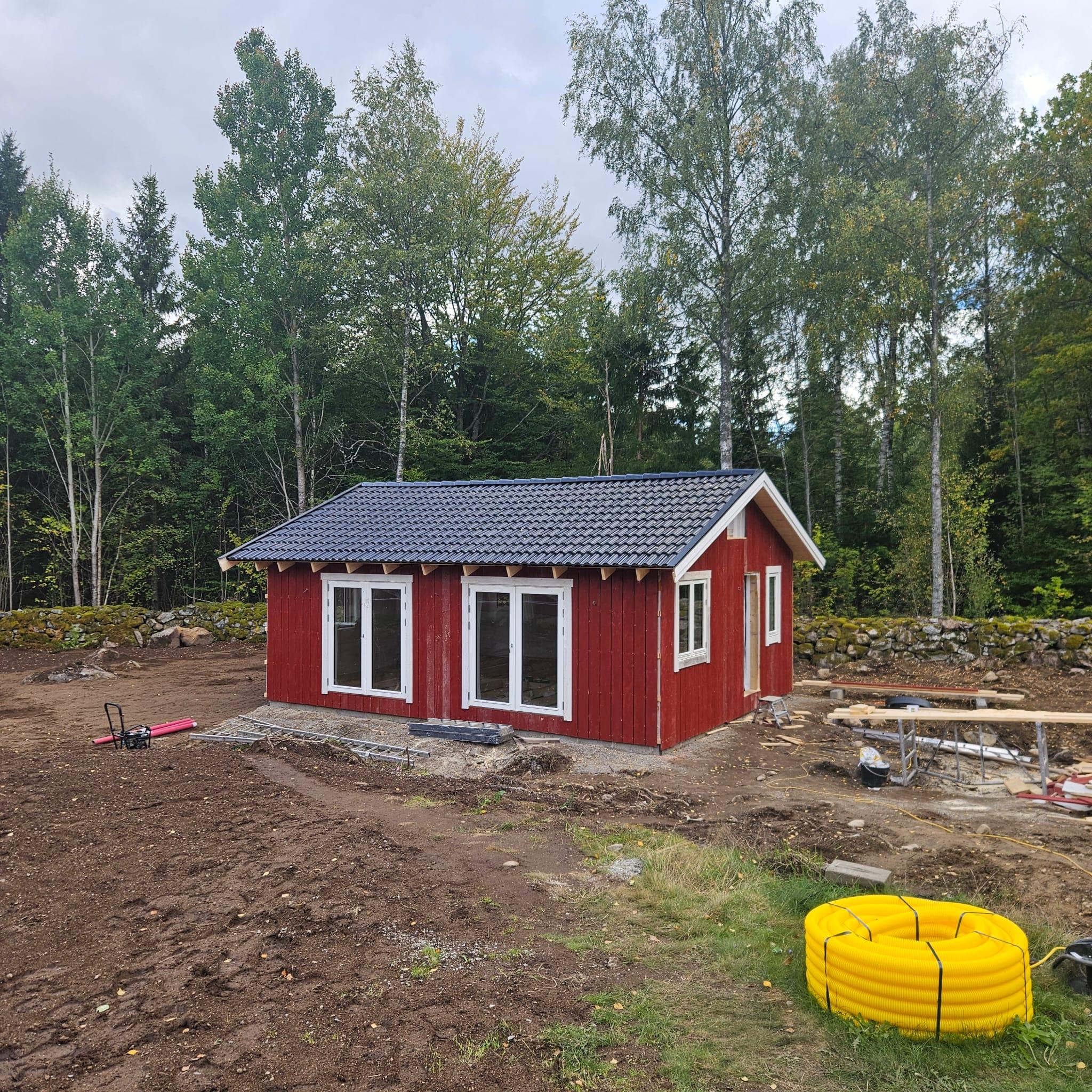 Attefallshuset med nytt tak, faluröd panel och vita fönster, klart på utsidan